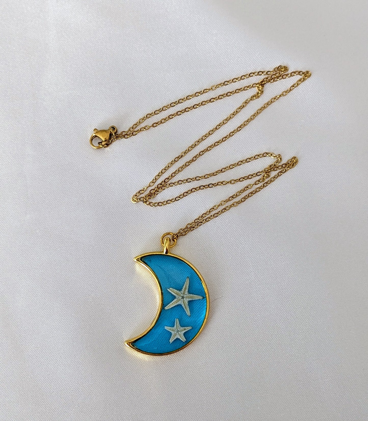 Collier fait main avec un coquillage incrusté dans la résine – bijou nature et bord de mer. En forme de lune