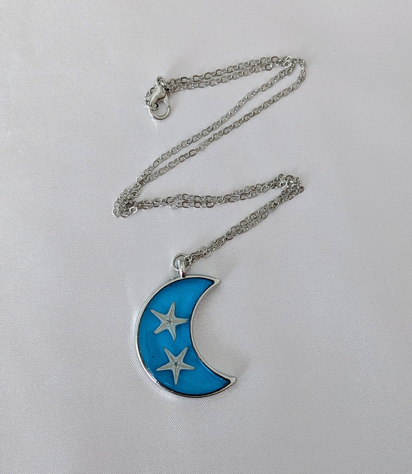 Collier fait main avec un coquillage incrusté dans la résine – bijou nature et bord de mer. En forme de lune
