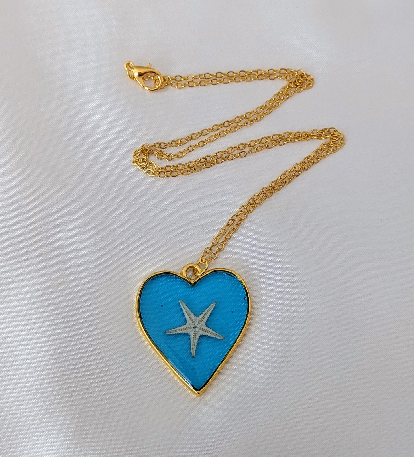 Collier fait main avec un coquillage incrusté dans la résine – bijou nature et bord de mer. En forme de cœur