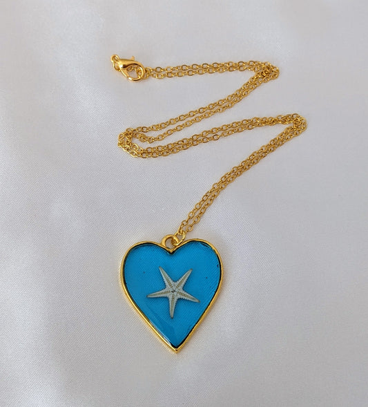Collier fait main avec un coquillage incrusté dans la résine – bijou nature et bord de mer. En forme de cœur