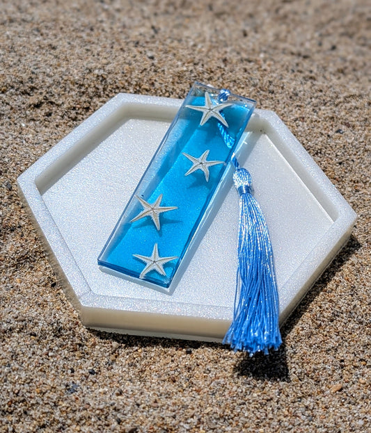 Marque-page artisanal en résine avec coquillages et sable – thème océan, fait main en France.
