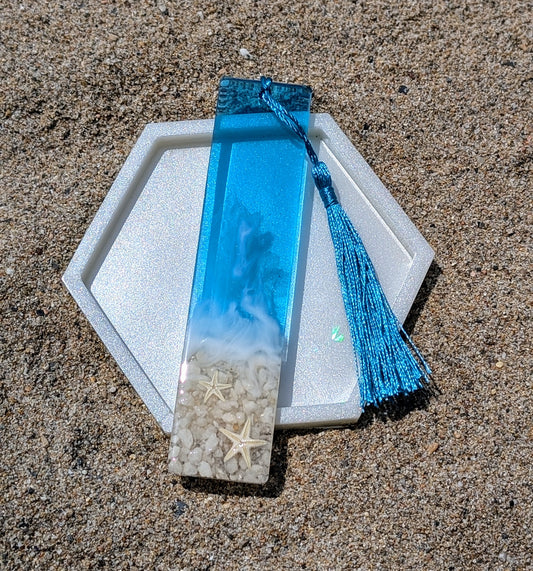 Marque-page artisanal en résine avec coquillages et sable – thème océan, fait main en France.