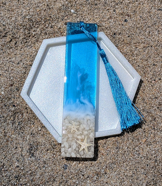 Marque-page artisanal en résine avec coquillages et sable – thème océan, fait main en France.