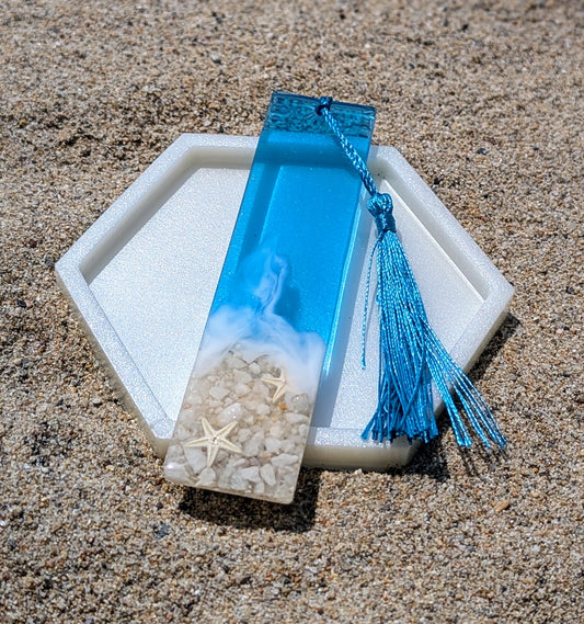 Marque-page artisanal en résine avec coquillages et sable – thème océan, fait main en France.