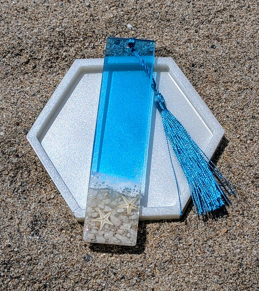 Marque-page artisanal en résine avec coquillages et sable – thème océan, fait main en France.