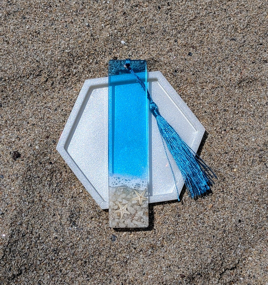 Marque-page artisanal en résine avec coquillages et sable – thème océan, fait main en France.