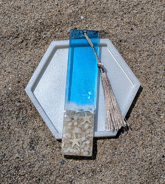 Marque-page artisanal en résine avec coquillages et sable – thème océan, fait main en France.